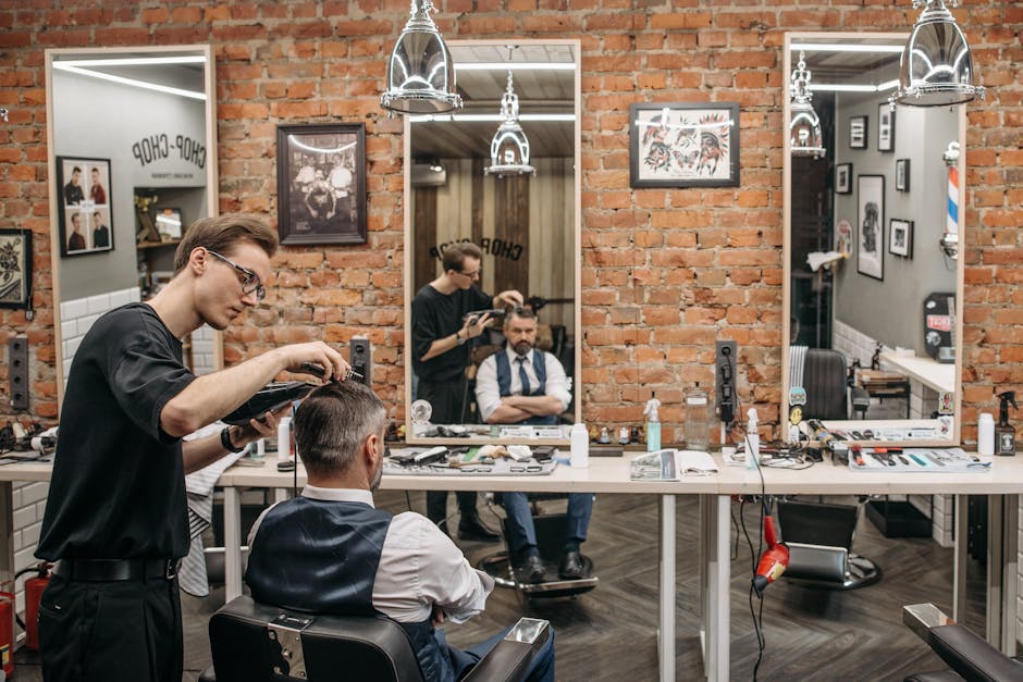 A barber expertly cutting a man's hair in a stylish, contemporary salon with exposed brick walls.