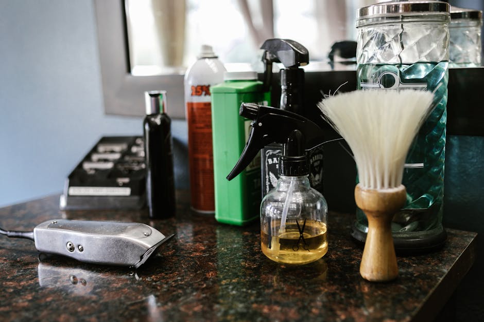 Close-up of barber tools on counter including clippers, spray bottle, and brush in a stylish barbershop.