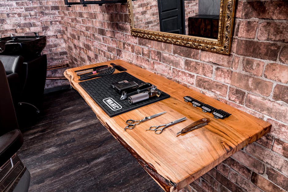 A set of professional hair styling tools neatly arranged on a wooden table in a trendy barbershop.