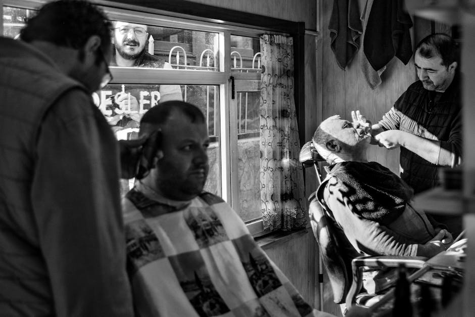 A black and white photo capturing a lively barbershop scene with barbers and clients.